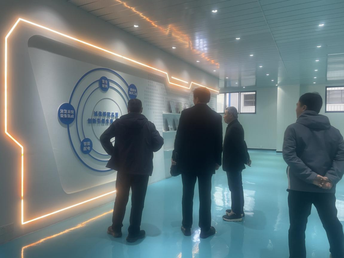 Фото: Делегация знакомится с организационной структурой компании и философией ее развития перед стеной, посвященной корпоративной культуре.