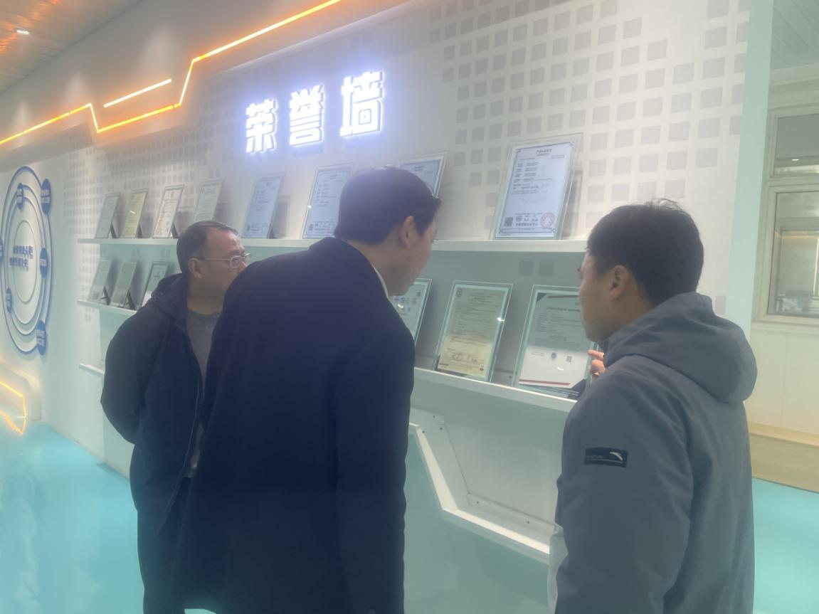 Фото: Делегация изучает квалификационные документы и почетные грамоты компании перед стеной почета.