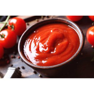 Delicious ketchup in bowl with ingredients on tray, closeup